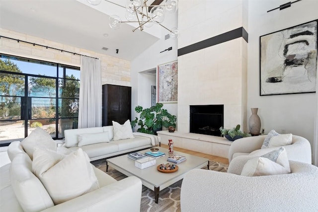 living room featuring high vaulted ceiling, a notable chandelier, visible vents, and a tile fireplace