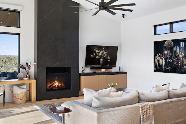 living room with a ceiling fan, wood finished floors, a wealth of natural light, and a large fireplace