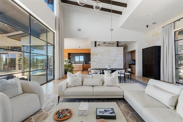 living room featuring beamed ceiling, high vaulted ceiling, visible vents, and wood finished floors
