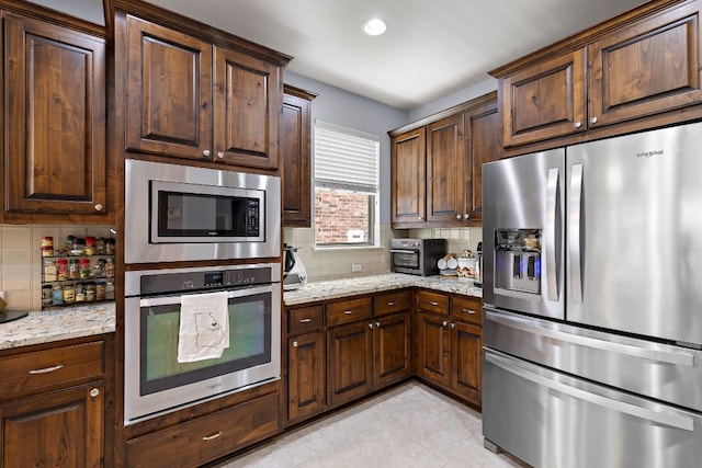 kitchen with light stone countertops, appliances with stainless steel finishes, and decorative backsplash