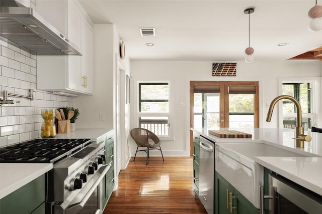 kitchen with wall chimney range hood, visible vents, appliances with stainless steel finishes, light countertops, and beverage cooler