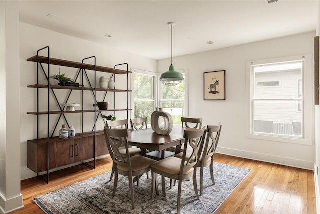 dining space with baseboards and light wood-type flooring