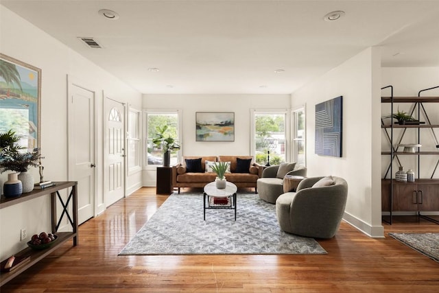 living room featuring visible vents, baseboards, wood finished floors, and a wealth of natural light
