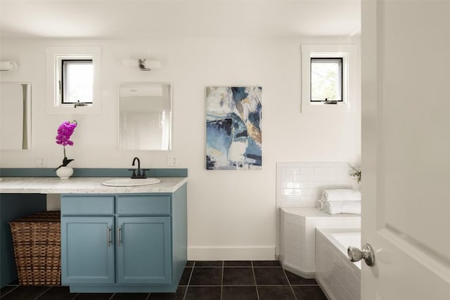 bathroom featuring a relaxing tiled tub, tile patterned floors, baseboards, and vanity