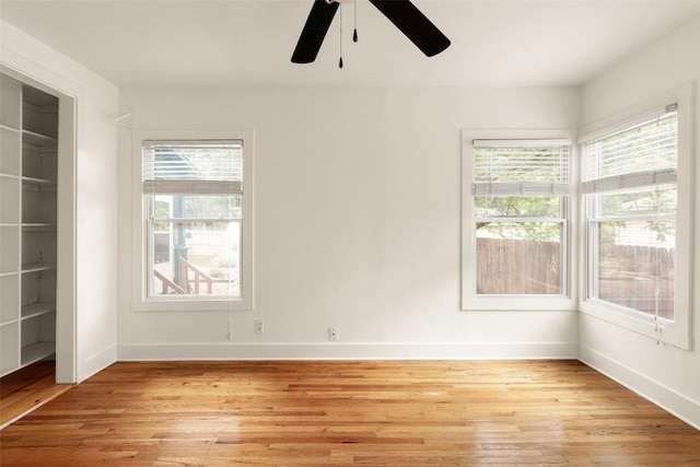 spare room with baseboards, light wood-style flooring, and ceiling fan