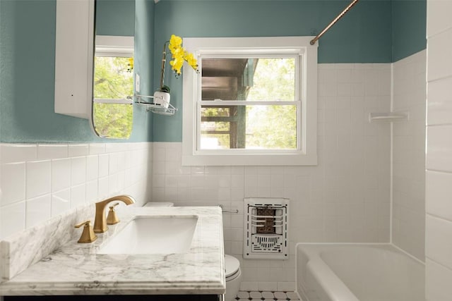 bathroom with toilet, tile walls, a wealth of natural light, and vanity