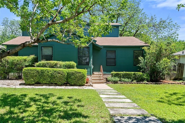 view of front facade featuring a shingled roof and a front yard