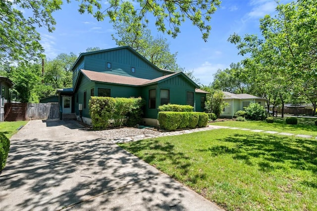 view of front of property featuring board and batten siding, fence, driveway, and a front lawn