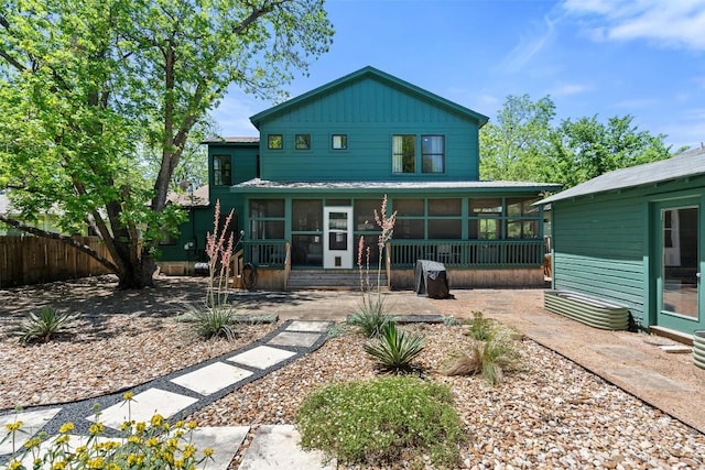 rear view of property featuring fence, a patio, and a sunroom