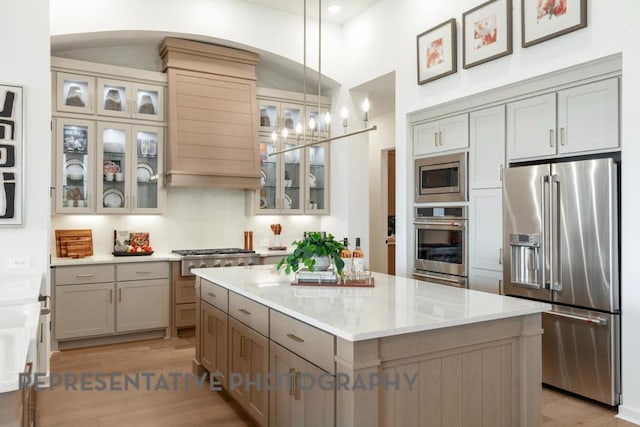 kitchen featuring gray cabinetry, a center island, stainless steel appliances, and light wood-style flooring
