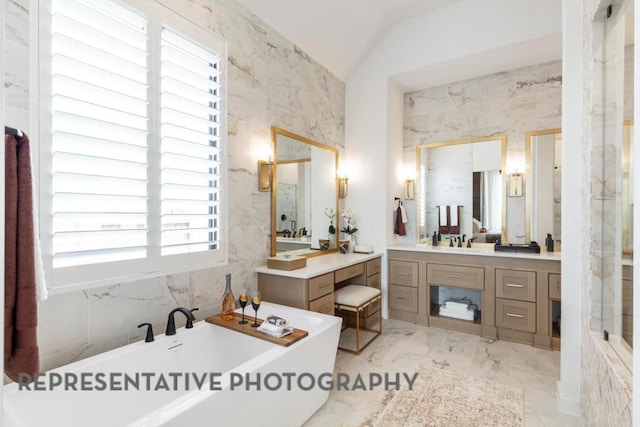 full bathroom featuring vanity, a freestanding tub, vaulted ceiling, and marble finish floor