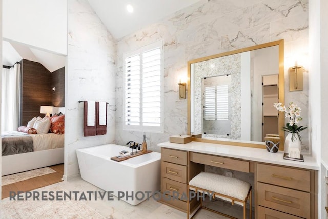 ensuite bathroom featuring a wealth of natural light, ensuite bathroom, a soaking tub, and lofted ceiling