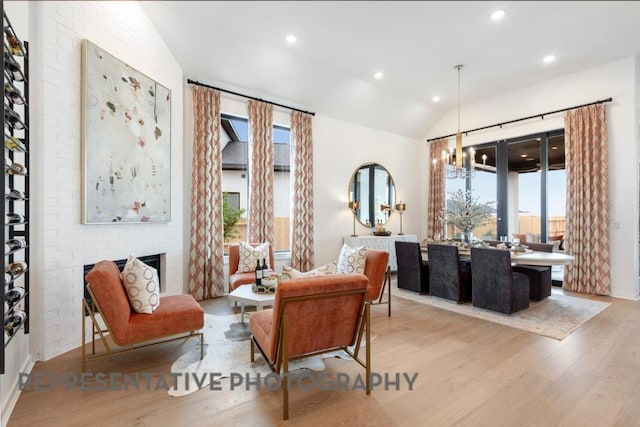 sitting room featuring a brick fireplace, recessed lighting, wood finished floors, and lofted ceiling