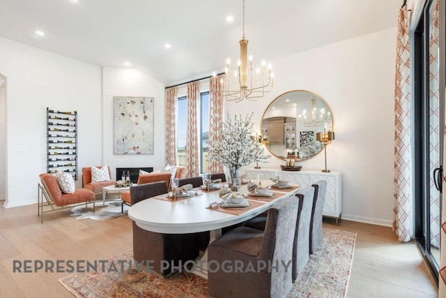 dining room with a notable chandelier, baseboards, lofted ceiling, recessed lighting, and light wood-style flooring