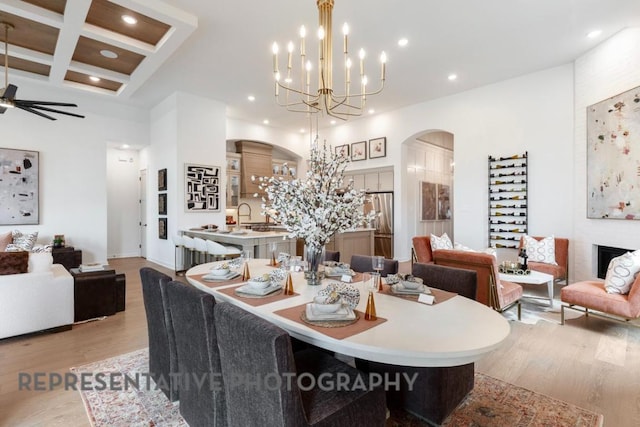 dining room featuring recessed lighting, arched walkways, light wood finished floors, and beam ceiling