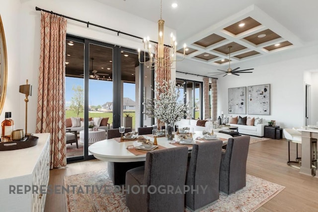 dining space featuring coffered ceiling, ceiling fan with notable chandelier, wood finished floors, and beamed ceiling