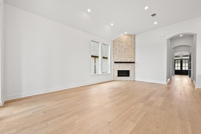 250 Leaning Rock Rdg, Austin, TX 78737 - unfurnished living room featuring healthy amount of natural light, light wood-type flooring, arched walkways, lofted ceiling, and a fireplace