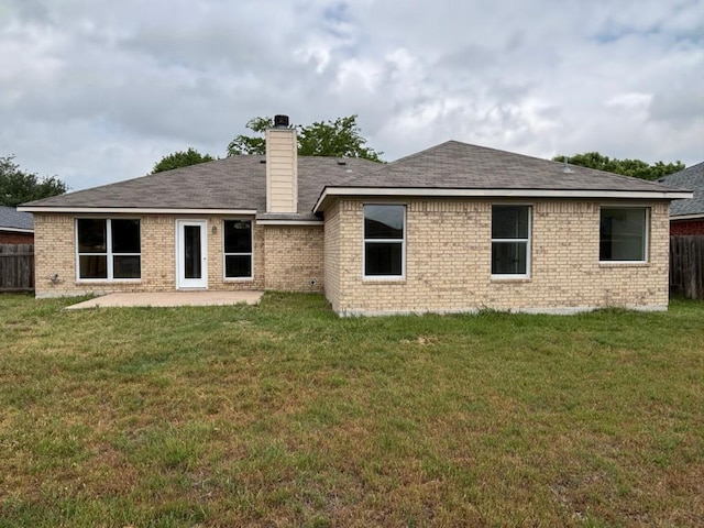 back of house with a lawn, brick siding, fence, and a patio area