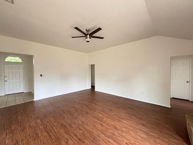 unfurnished living room featuring ceiling fan, vaulted ceiling, and wood finished floors