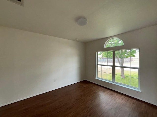 spare room with dark wood-style flooring, baseboards, and visible vents