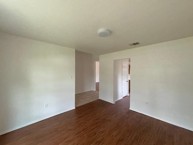 empty room featuring baseboards, visible vents, and wood finished floors