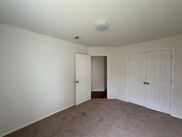 unfurnished bedroom with carpet floors, baseboards, visible vents, and a closet