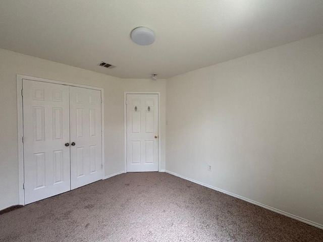 unfurnished bedroom with carpet floors, baseboards, visible vents, and a closet