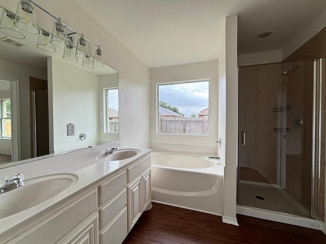 full bathroom featuring visible vents, a shower stall, a sink, and wood finished floors