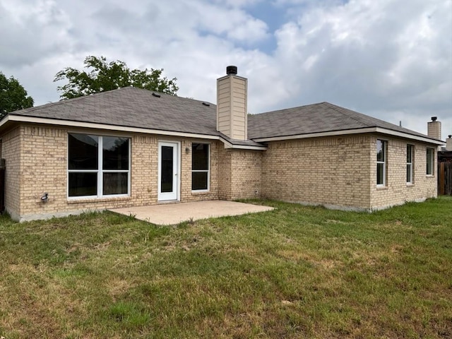 back of property featuring a patio, brick siding, a lawn, and a chimney