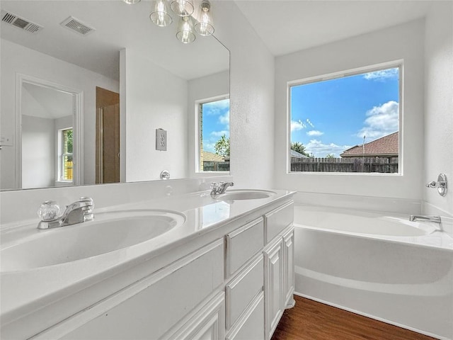 1614 Prickly Pear St, Lockhart, TX 78644 - bathroom with a bath, double vanity, wood finished floors, and a chandelier