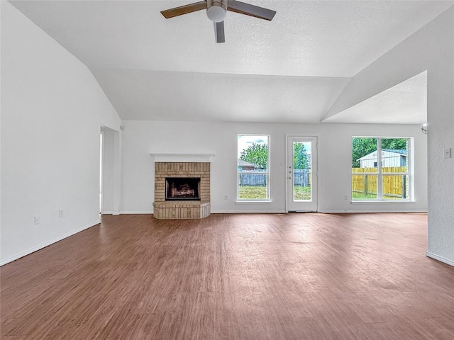 1614 Prickly Pear St, Lockhart, TX 78644 - unfurnished living room featuring lofted ceiling, wood finished floors, a ceiling fan, and a brick fireplace