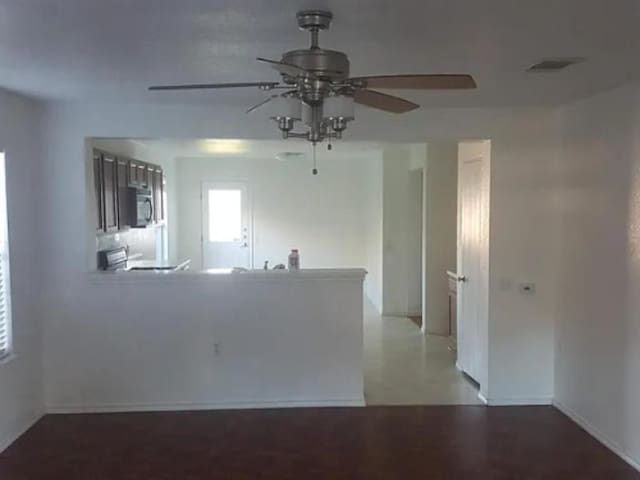 empty room featuring baseboards, ceiling fan, and visible vents