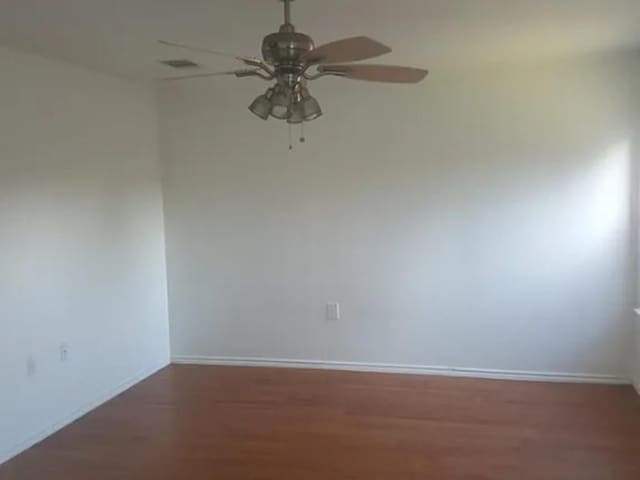 empty room with baseboards, ceiling fan, and wood finished floors