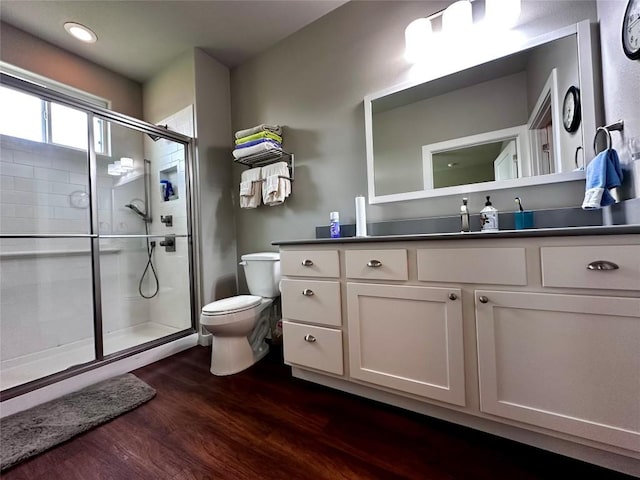 bathroom with vanity, toilet, wood finished floors, and a stall shower