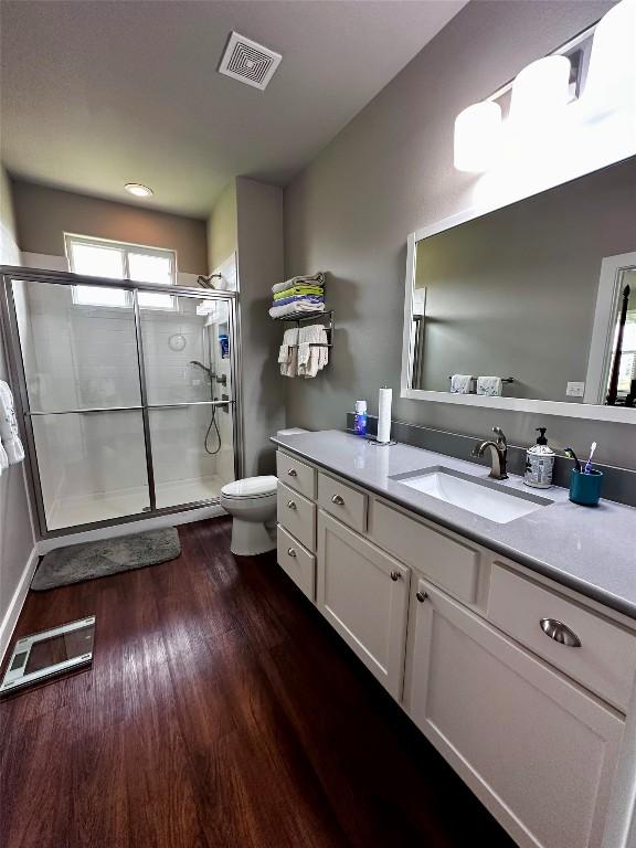 full bathroom with visible vents, a stall shower, toilet, and wood finished floors