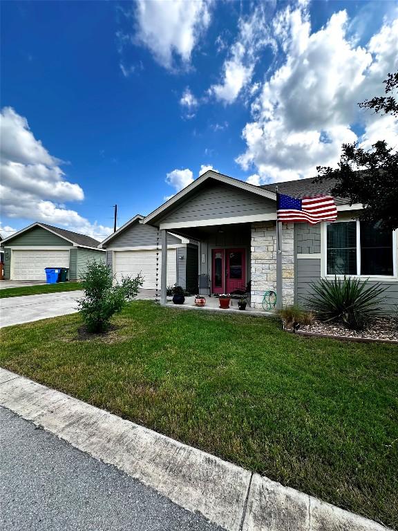 ranch-style house with an attached garage, driveway, a front lawn, and stone siding