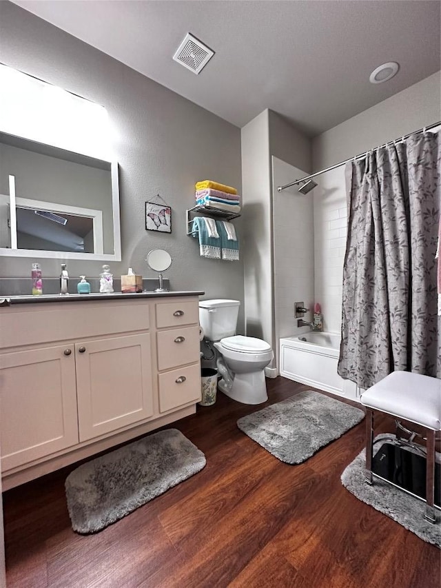 bathroom with visible vents, vanity, wood finished floors, toilet, and shower / bath combo