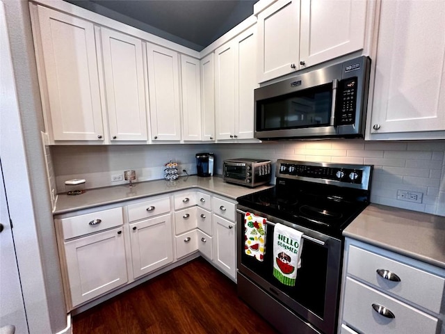 kitchen featuring a toaster, appliances with stainless steel finishes, dark wood-style floors, and white cabinetry