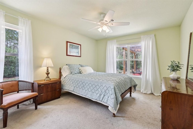 bedroom featuring light colored carpet, a ceiling fan, and multiple windows