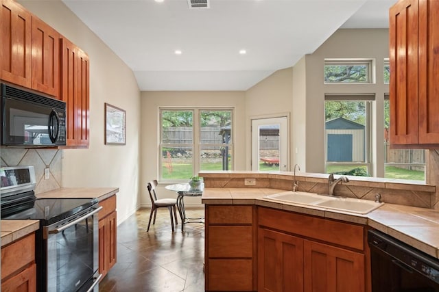 kitchen featuring a sink, tile countertops, a peninsula, backsplash, and black appliances