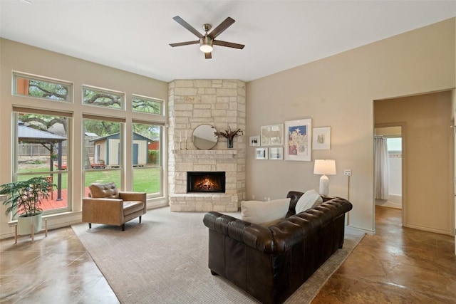 living area featuring a stone fireplace and ceiling fan