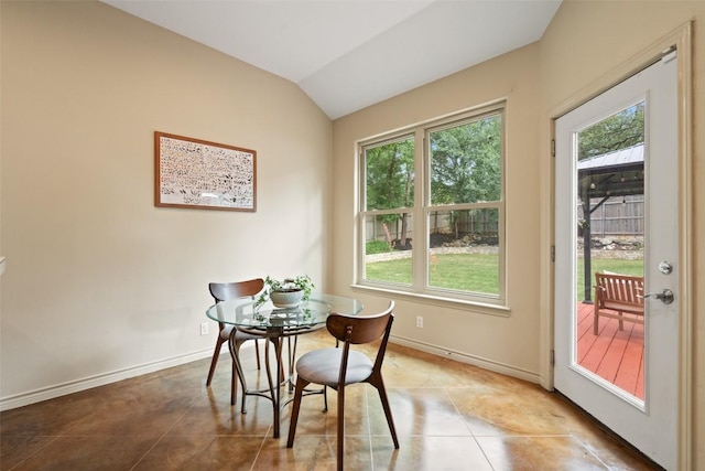 dining space featuring a healthy amount of sunlight, tile patterned floors, baseboards, and vaulted ceiling