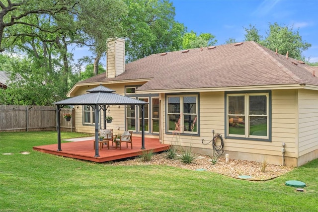 rear view of property featuring a chimney, a wooden deck, a gazebo, fence, and a yard