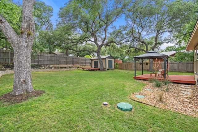 view of yard featuring a gazebo, a shed, a deck, a fenced backyard, and an outbuilding