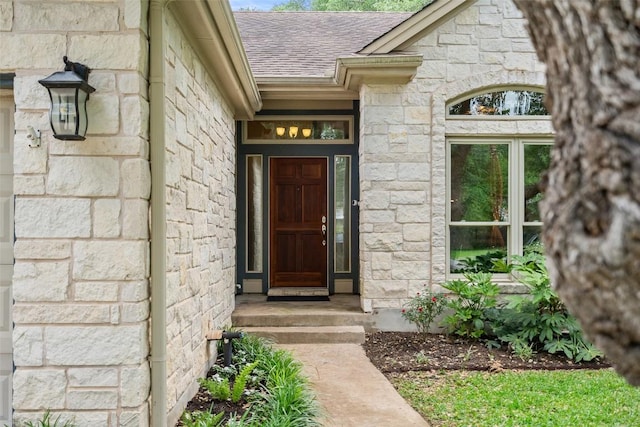 property entrance with a shingled roof and stone siding