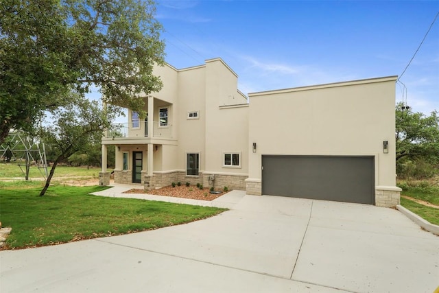 view of front of house with a balcony, a front lawn, concrete driveway, stone siding, and stucco siding