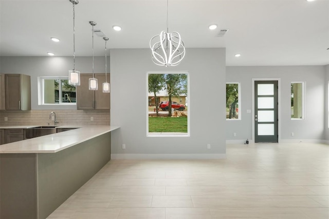 kitchen featuring a sink, light countertops, decorative backsplash, and a wealth of natural light