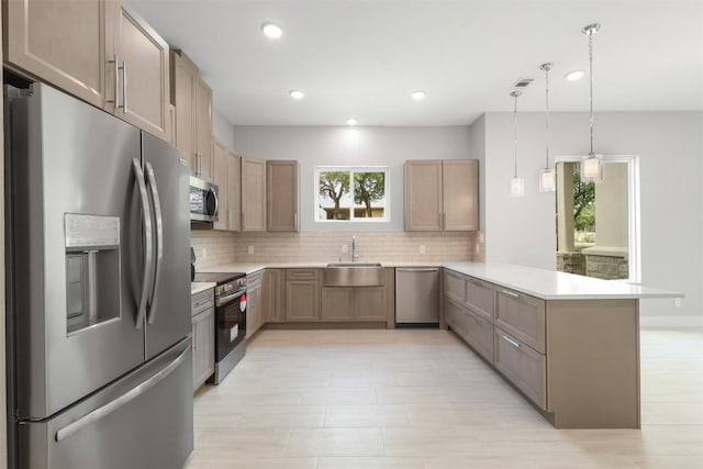 kitchen with decorative backsplash, a peninsula, light countertops, a sink, and appliances with stainless steel finishes