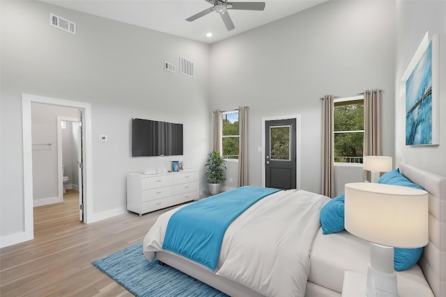 bedroom with visible vents, baseboards, light wood finished floors, a high ceiling, and recessed lighting