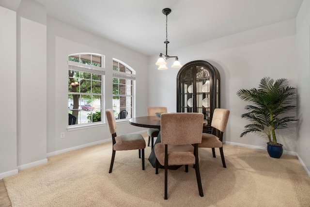 dining area with baseboards, an inviting chandelier, and light carpet